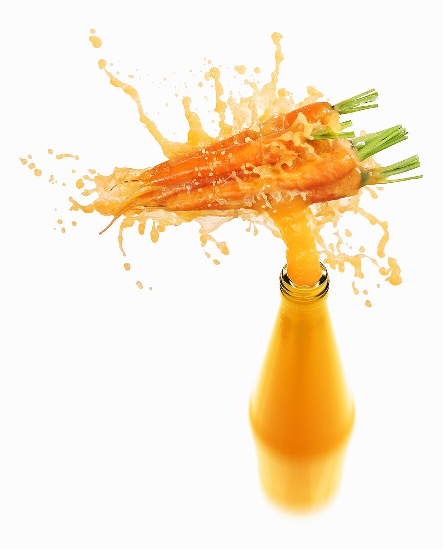 Carrot juice splashing out of bottle
