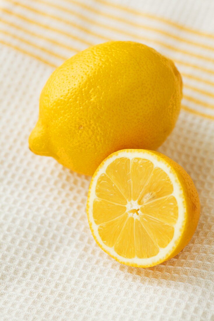 Ganze und halbe Zitrone auf Geschirrtuch