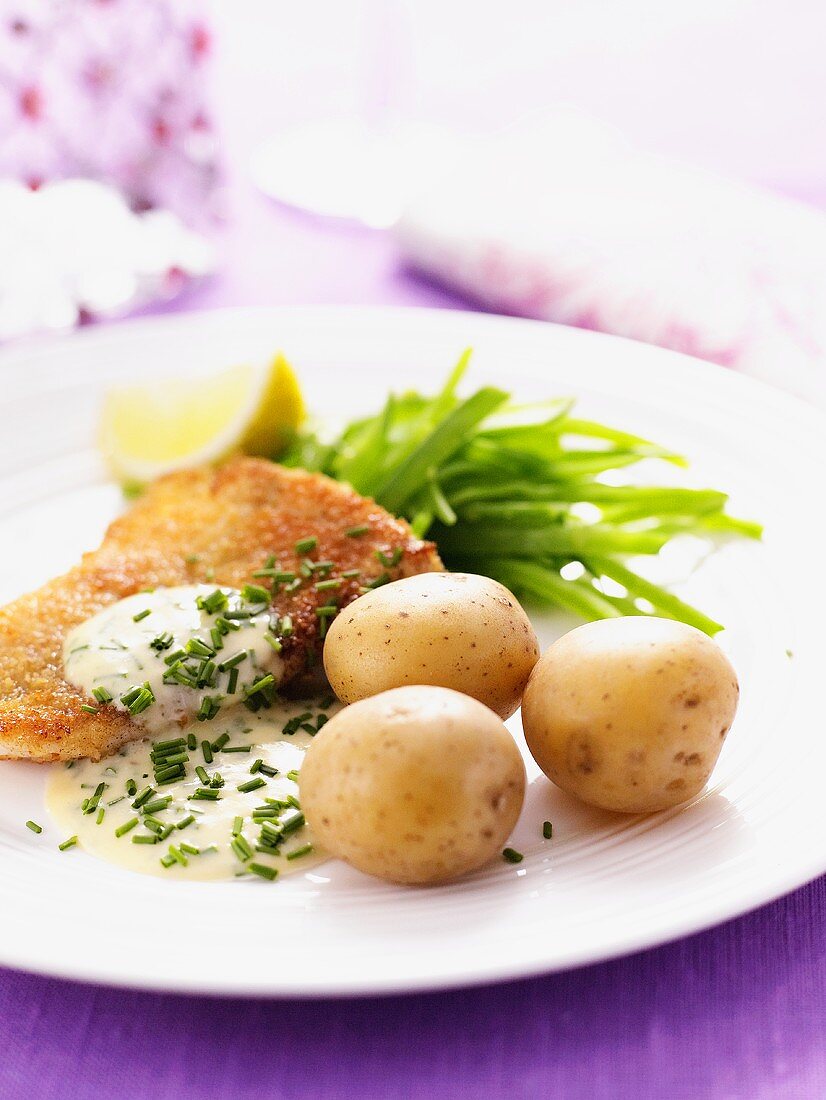 Breaded fish with chive sauce and potatoes