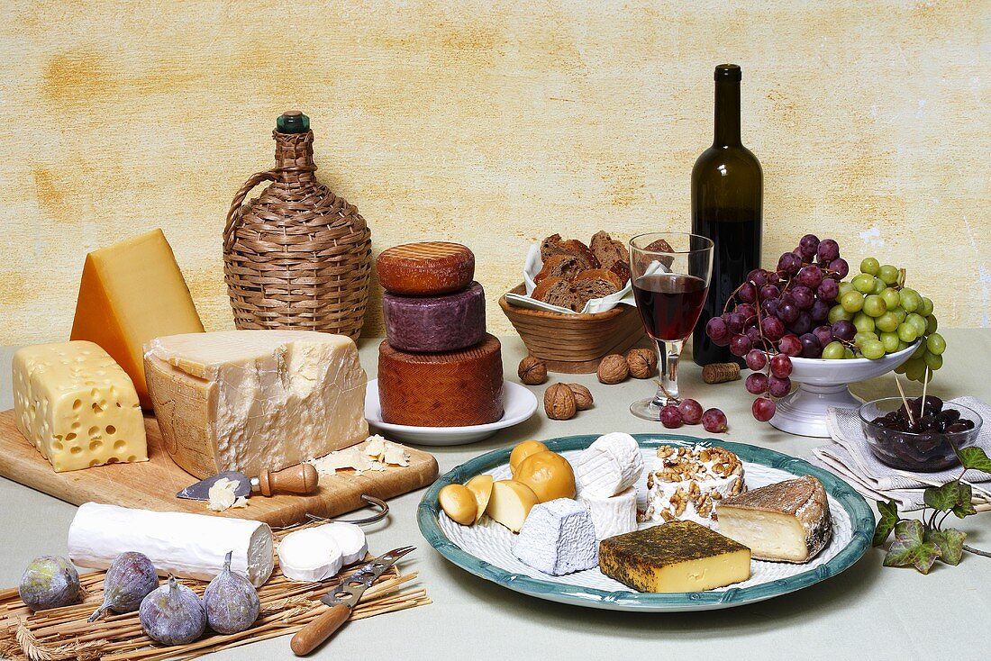 Cheese still life with bread, fruit, olives, nuts & red wine