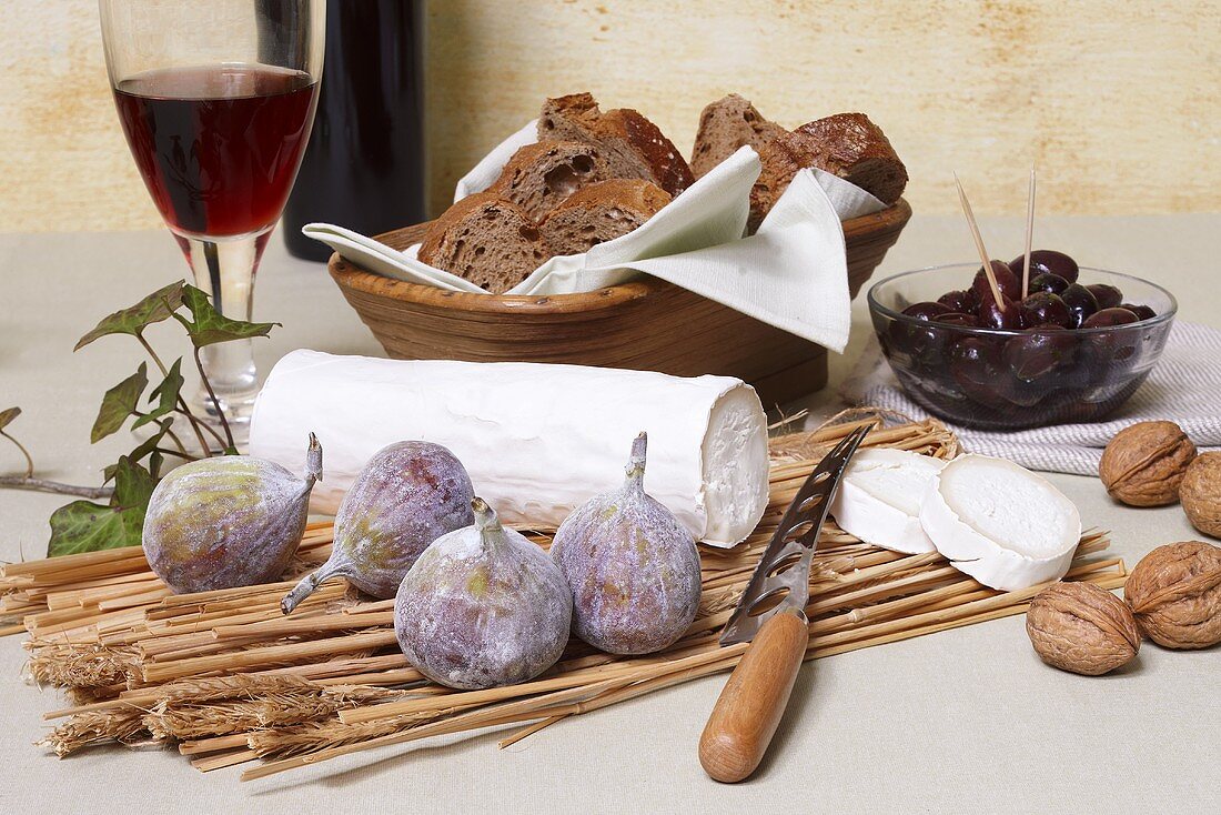 Ziegenkäserolle mit Feigen, Nüssen, Oliven, Brot und Rotwein