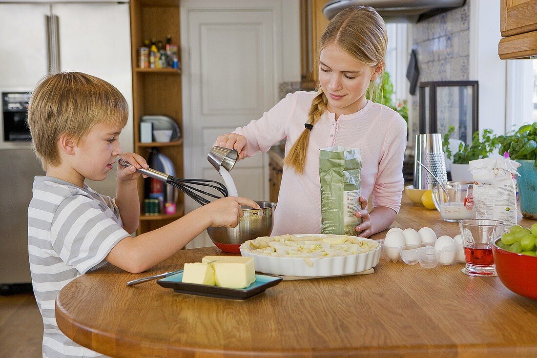 Two children baking a tart
