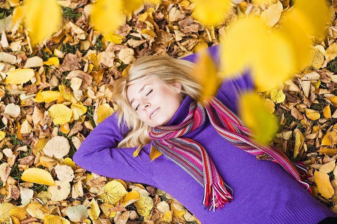 Frau liegt im Herbstlaub