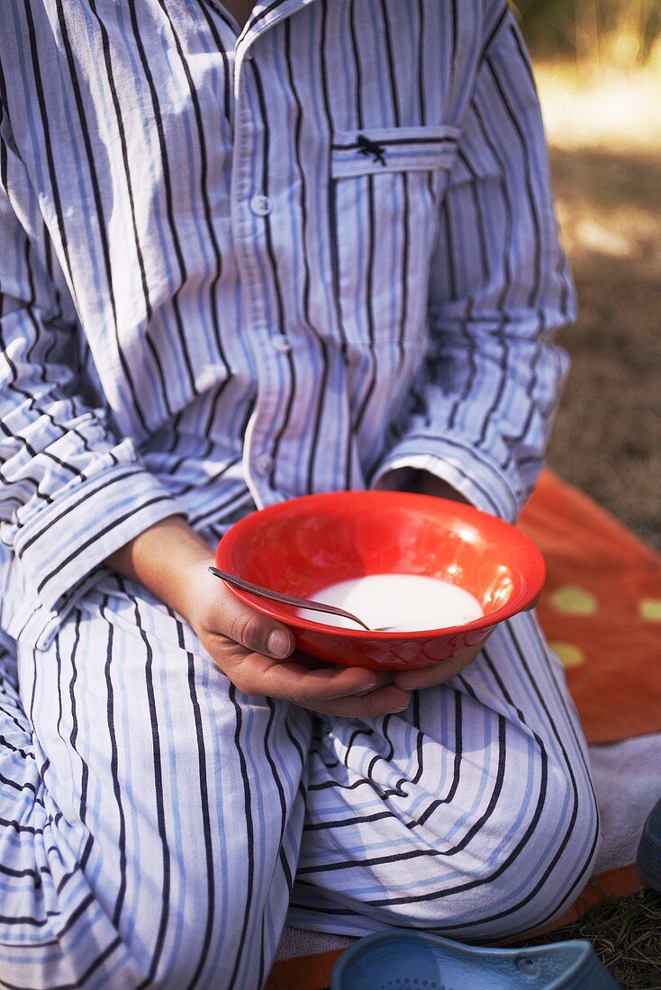 Junge hält ein Schälchen mit Milch