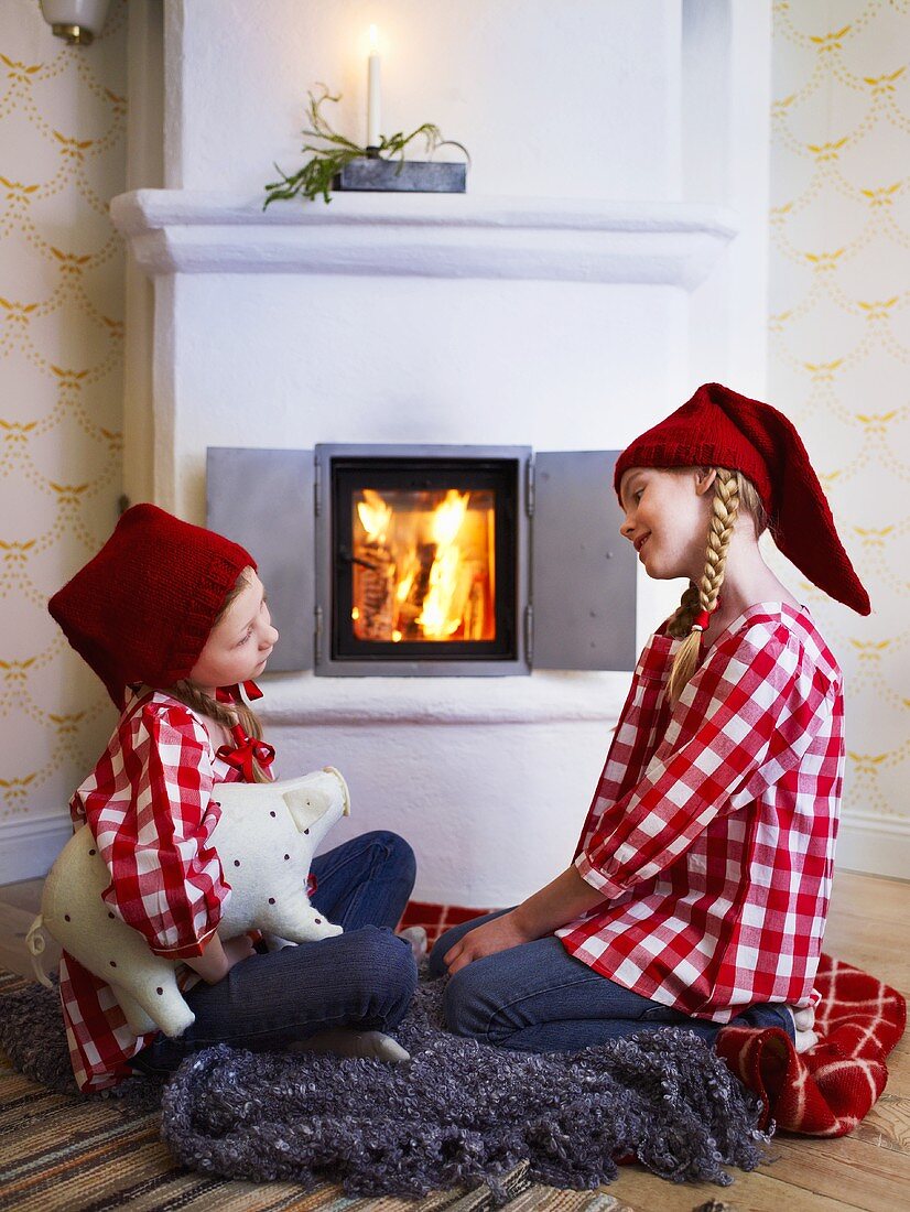 Two girls in Santa hats in front of fire