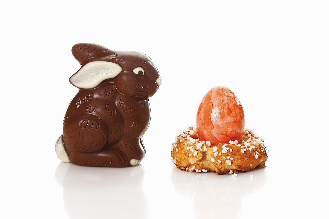 Coloured egg in baked egg cup and chocolate Easter Bunny