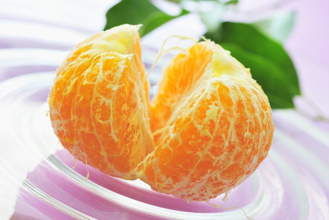 Peeled mandarin orange on glass plate