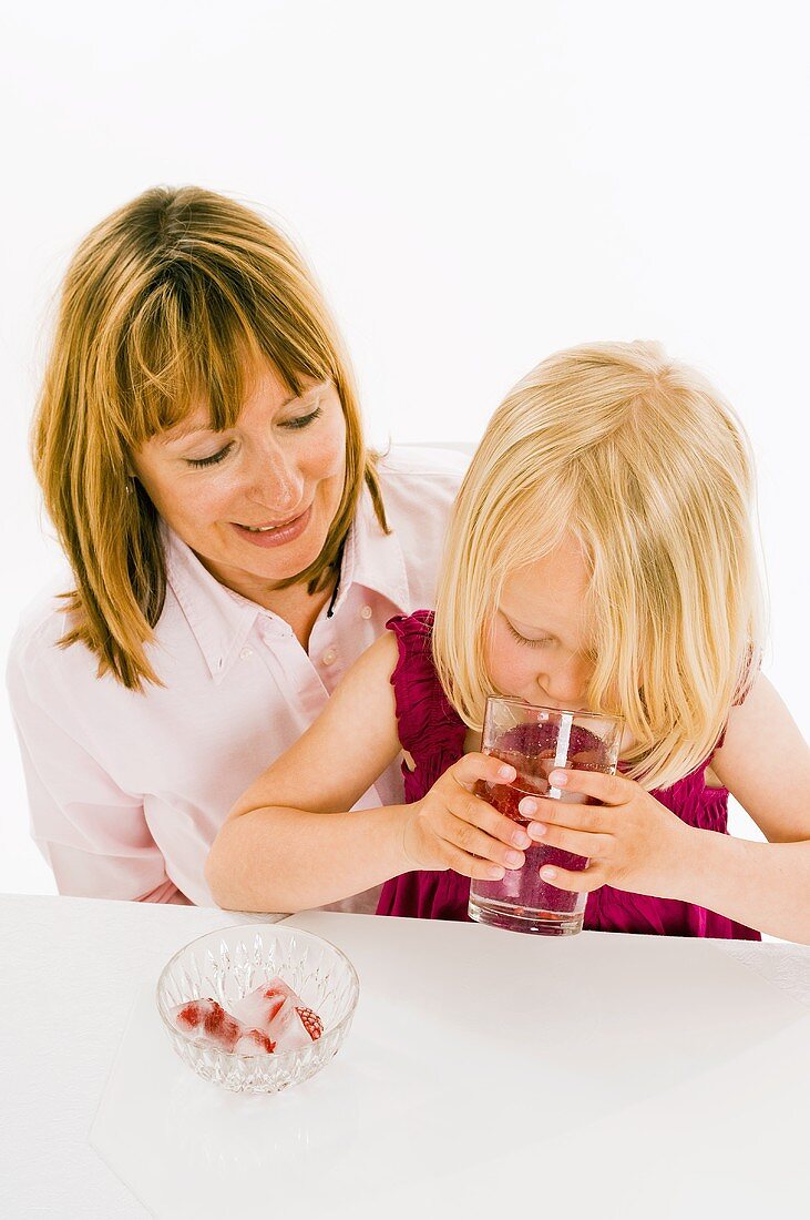 Girl drinking water with raspberry ice cubes