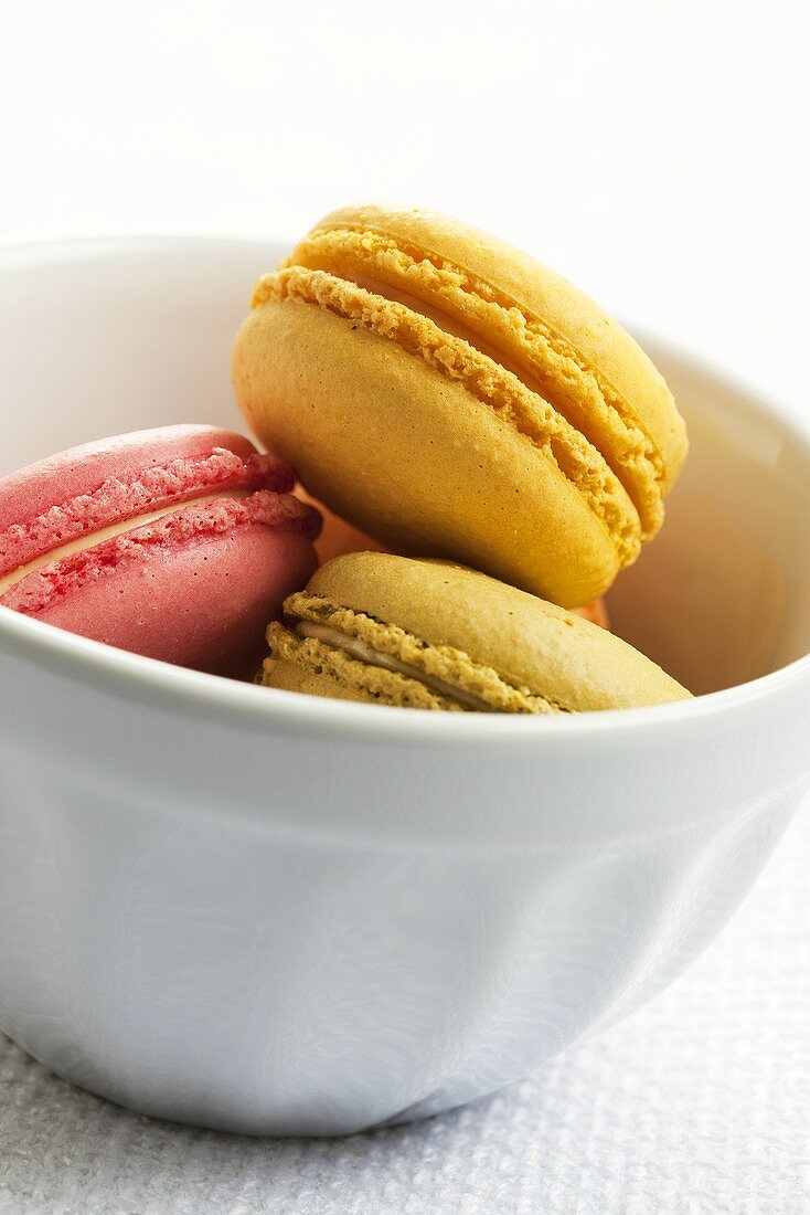 Different coloured macarons (small French cakes) in ceramic bowl
