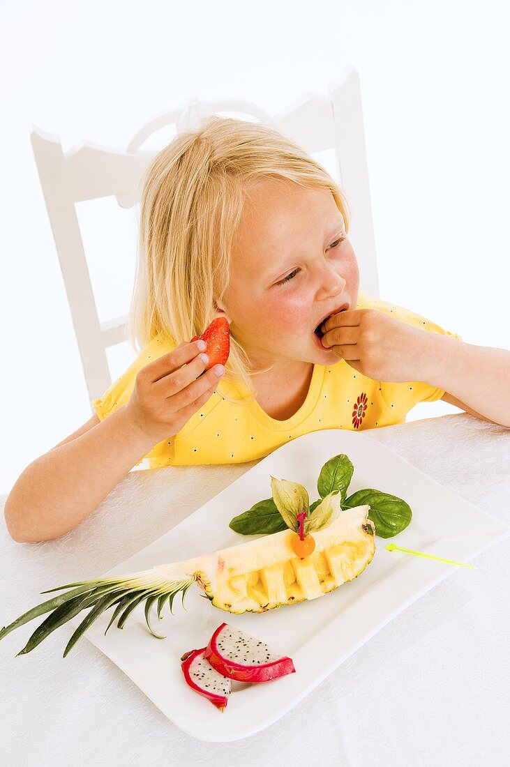 Girl eating fruit from plate