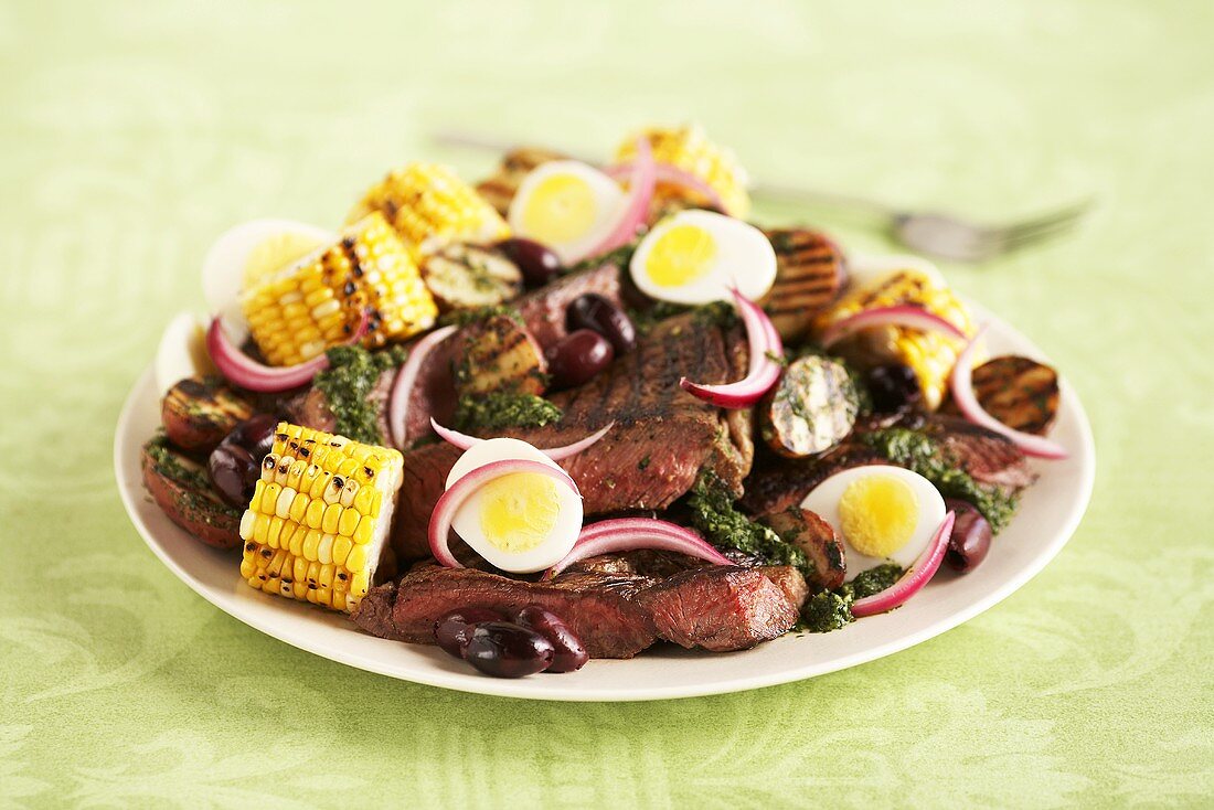 A beefsteak, corn, egg, olive and onion salad