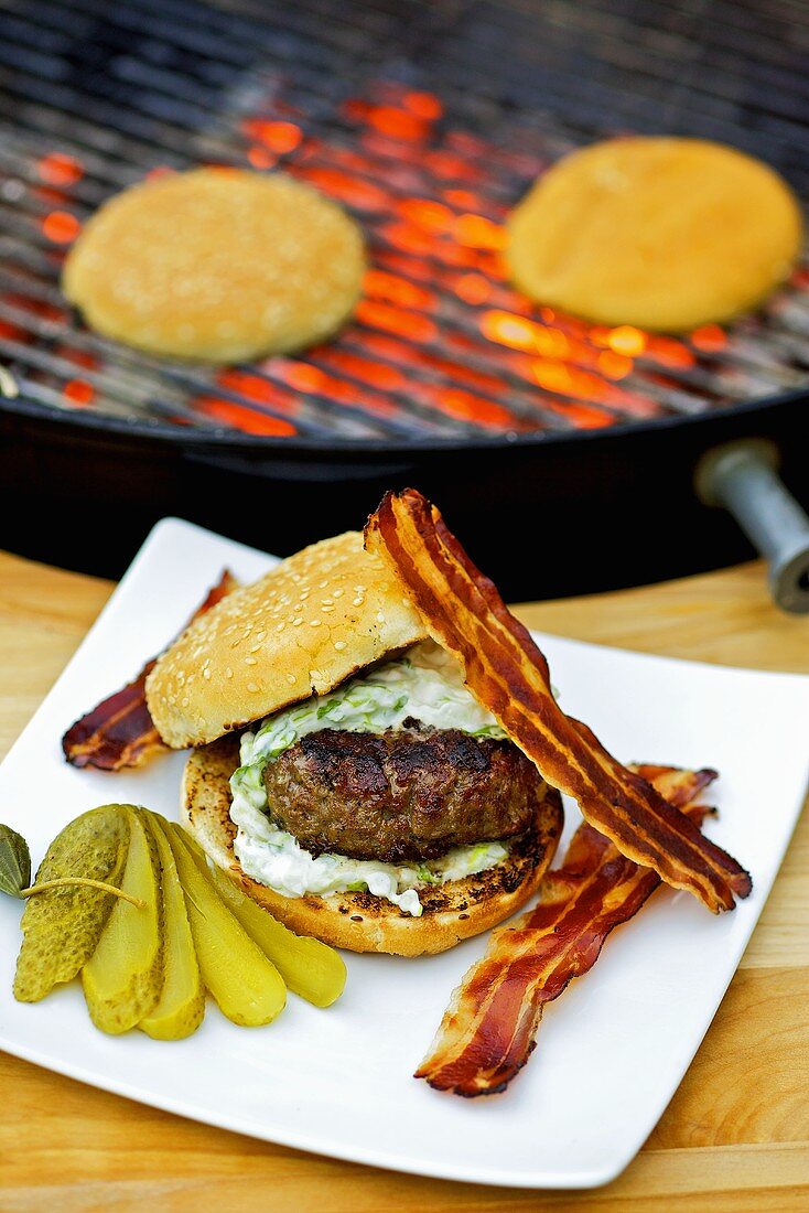 Barbecued hamburger with bacon and gherkin