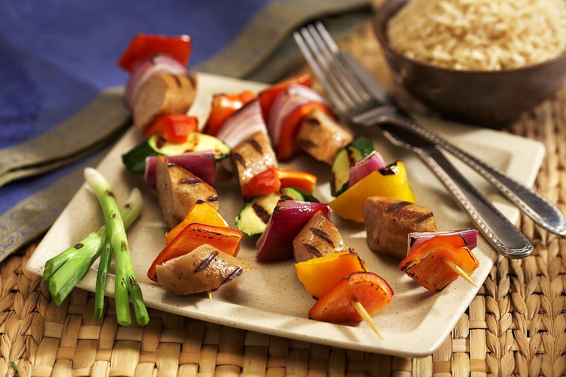 Grilled Sausage and Vegetable Kabobs on a Plate; Knife and Fork