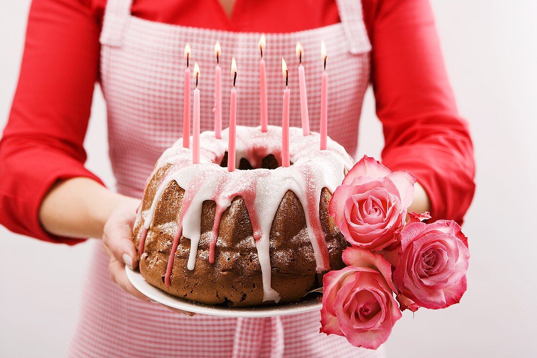 Frau hält Napfkuchen und Rosen zum Geburtstag