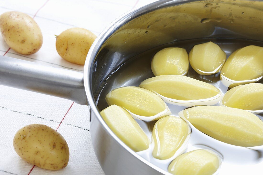 Kochtopf mit geschälten Kartoffeln und Wasser