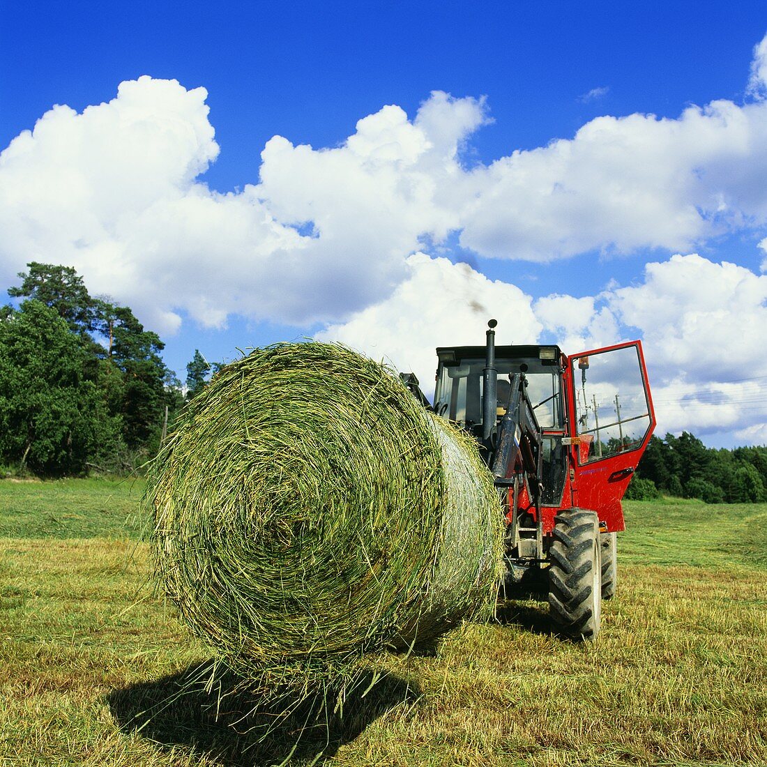 Traktor mit einem Heuballen auf dem Feld