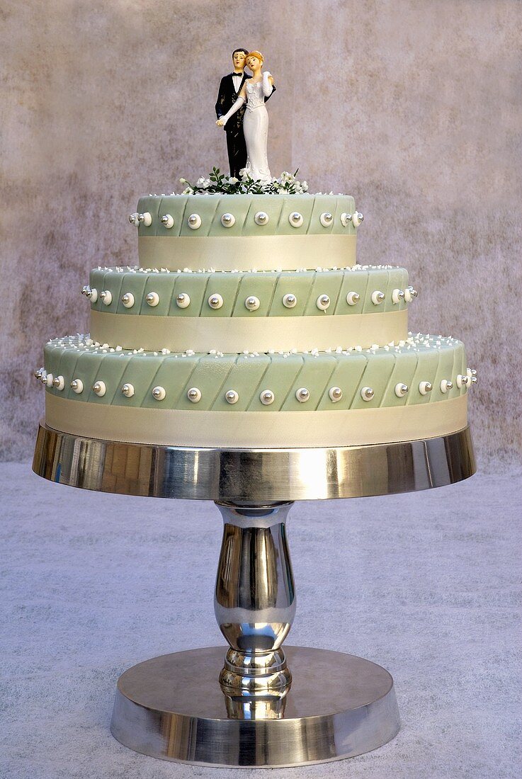 Three-tiered wedding cake with bride and groom cake toppers