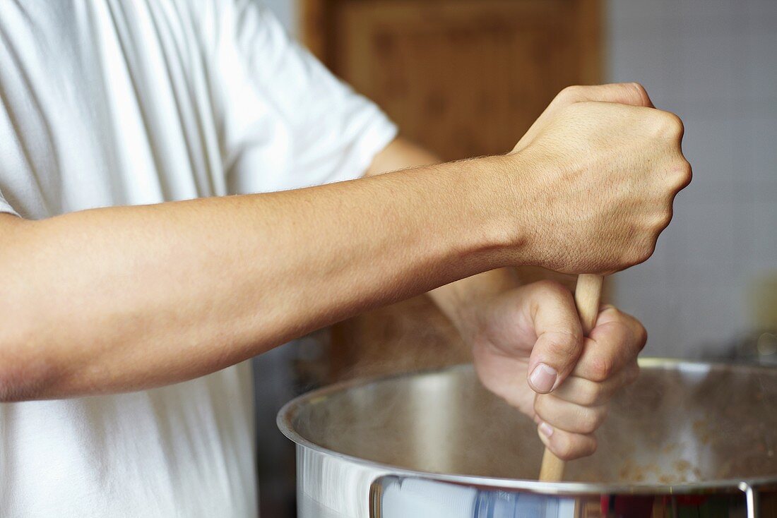 Chef stirring a pan with a wooden spoon