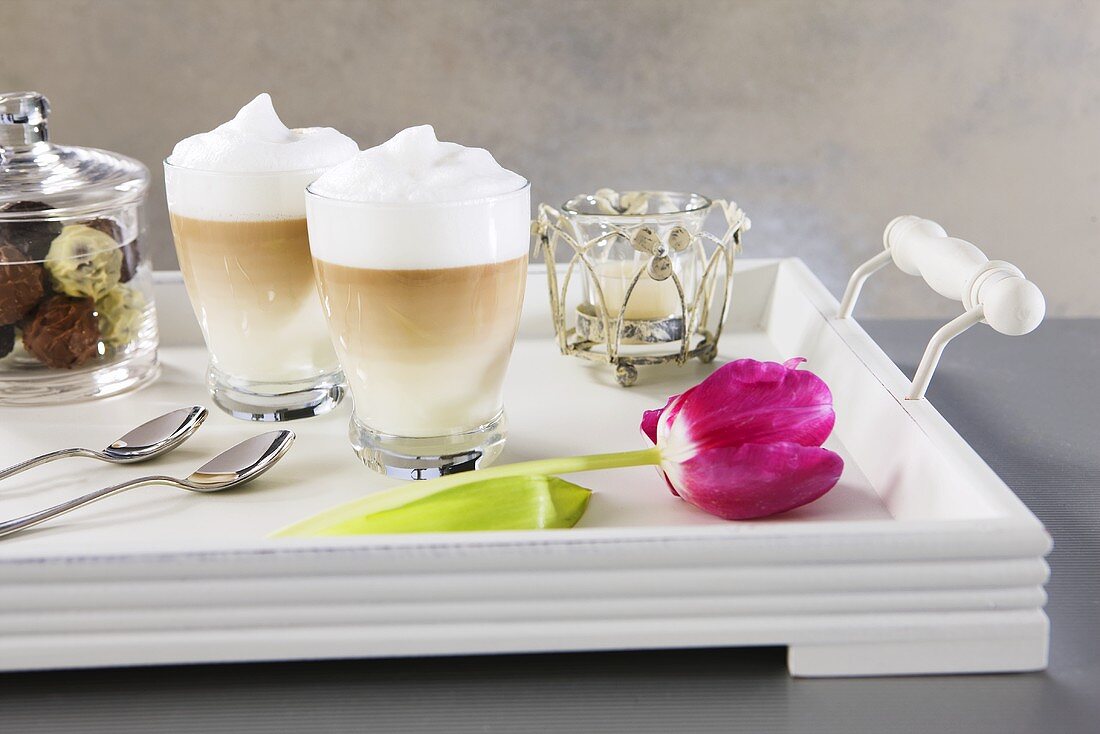 Caffe Latte, Pralinen, Tulpe und Windlicht auf Tablett