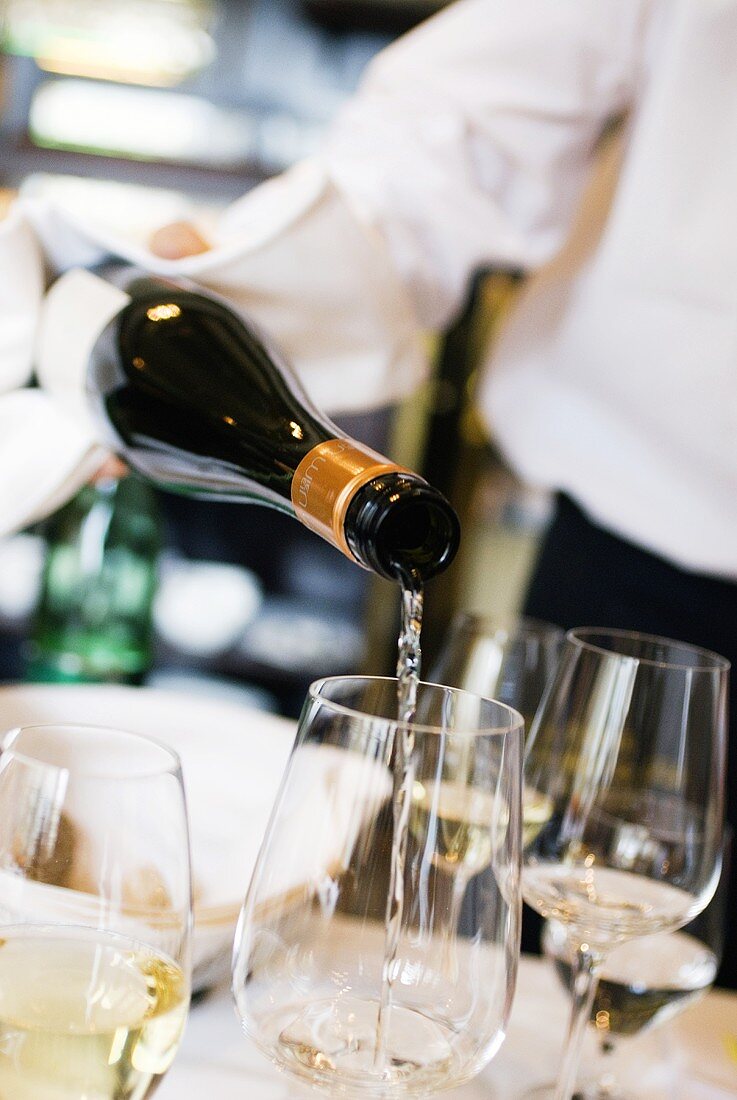 Waiter pouring white wine