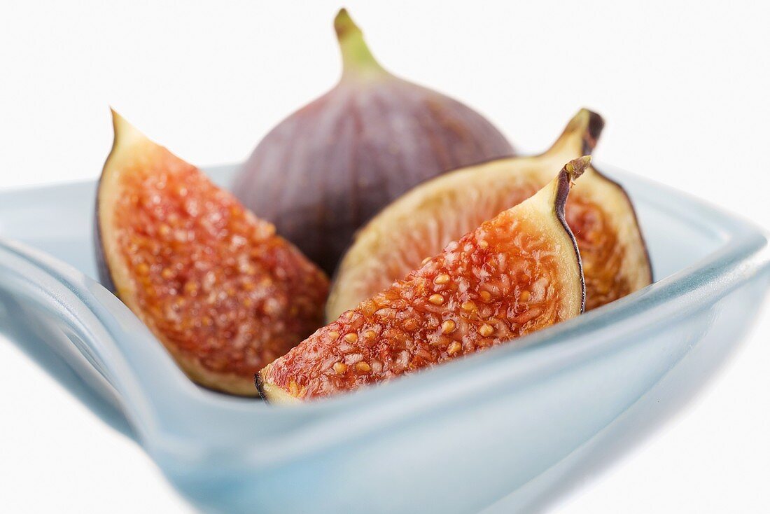 Fresh figs (whole, halved and quartered) in blue glass bowl