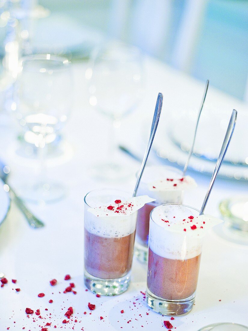 Cream desserts in glasses on laid table