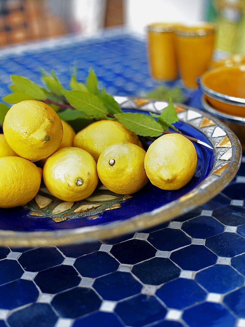 Several lemons with leaves in ceramic dish