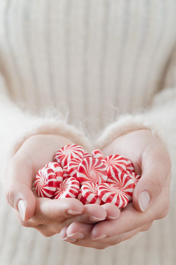 Hände halten rot-weiss gestreifte Pfefferminzbonbons