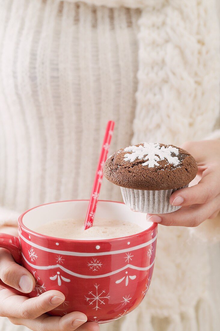 Frau hält Tasse Kakao und Schokoladenmuffin (weihnachtlich)