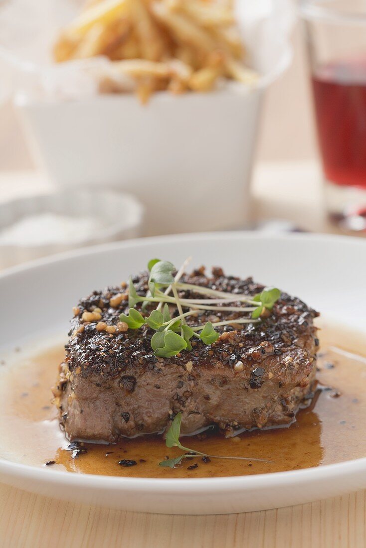 Peppered steak with cress, chips in background