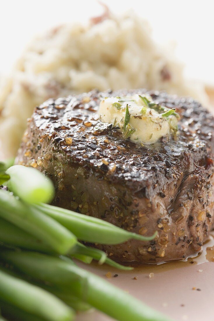 Peppered steak with herb butter, beans and mashed potato