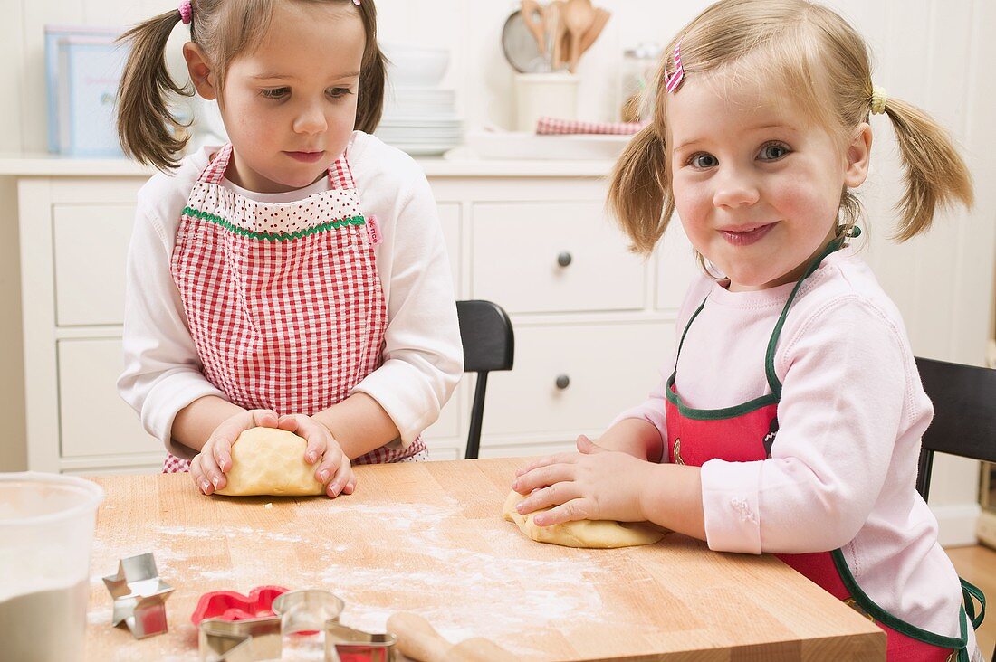 Two small girls kneading dough
