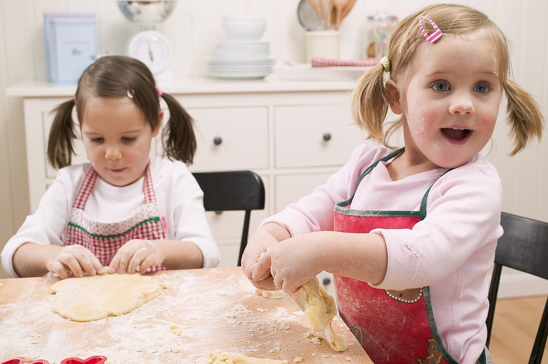 Two small girls kneading dough