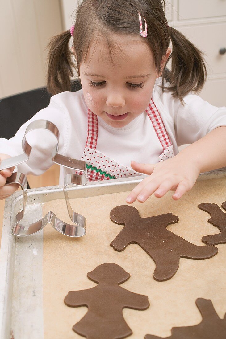 Kleines Mädchen legt Schokoladenplätzchen auf Backblech