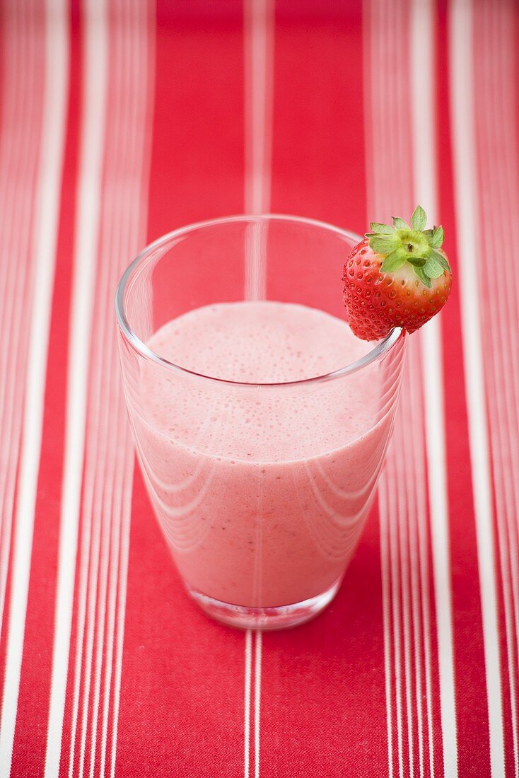 Strawberry milk in glass with fresh strawberry on rim