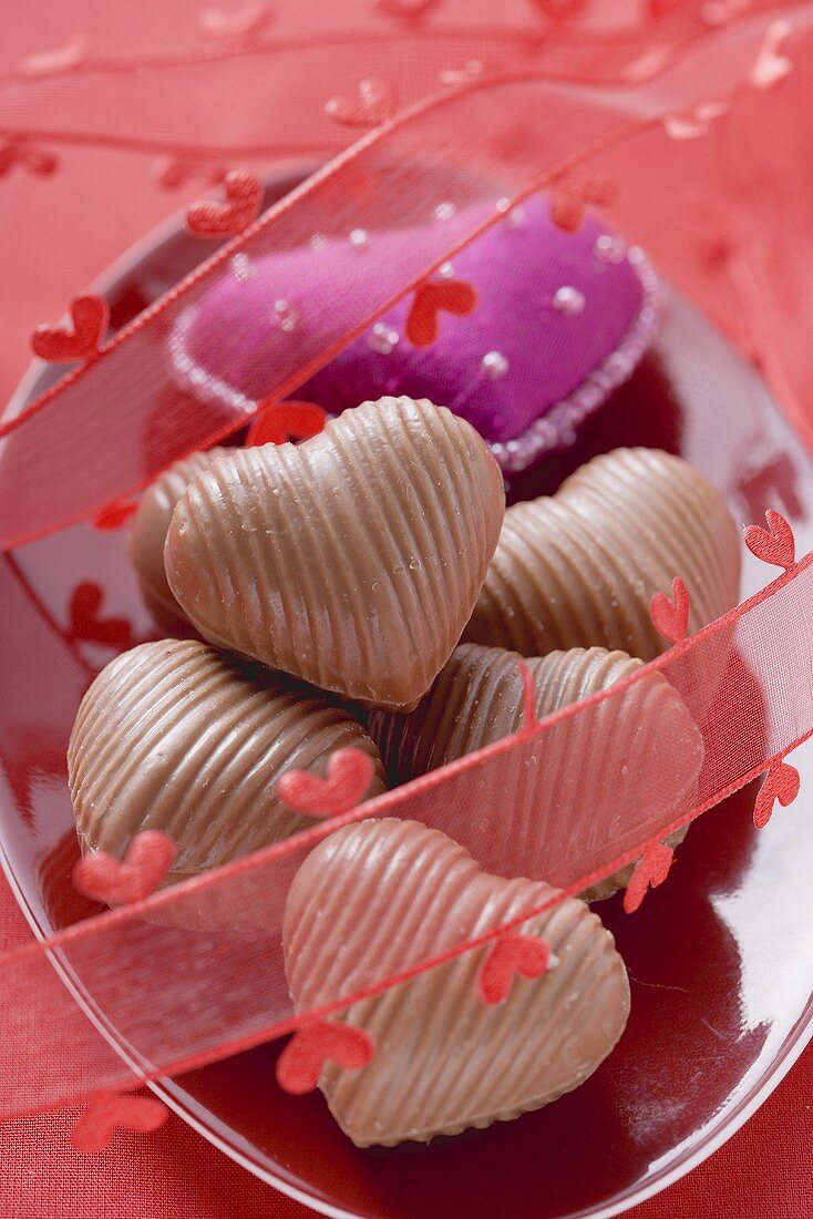 Violettes Stoffherz und Schokoladenpralinen zum Valentinstag