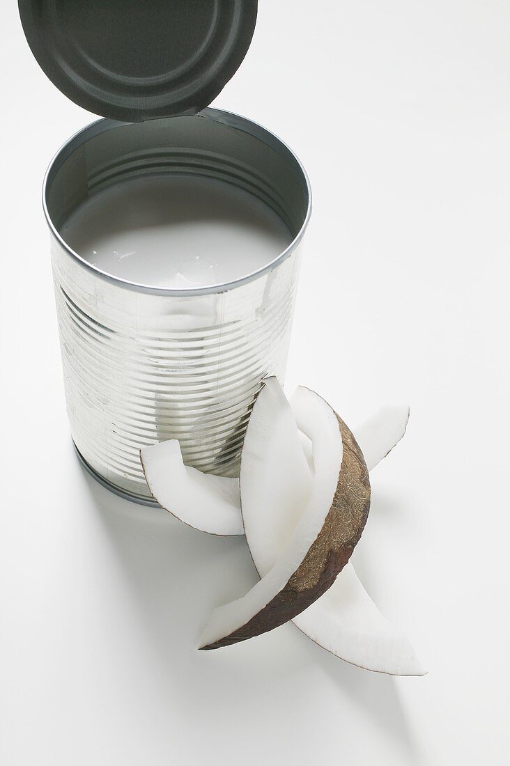 Coconut milk in a tin, wedge of coconut beside it