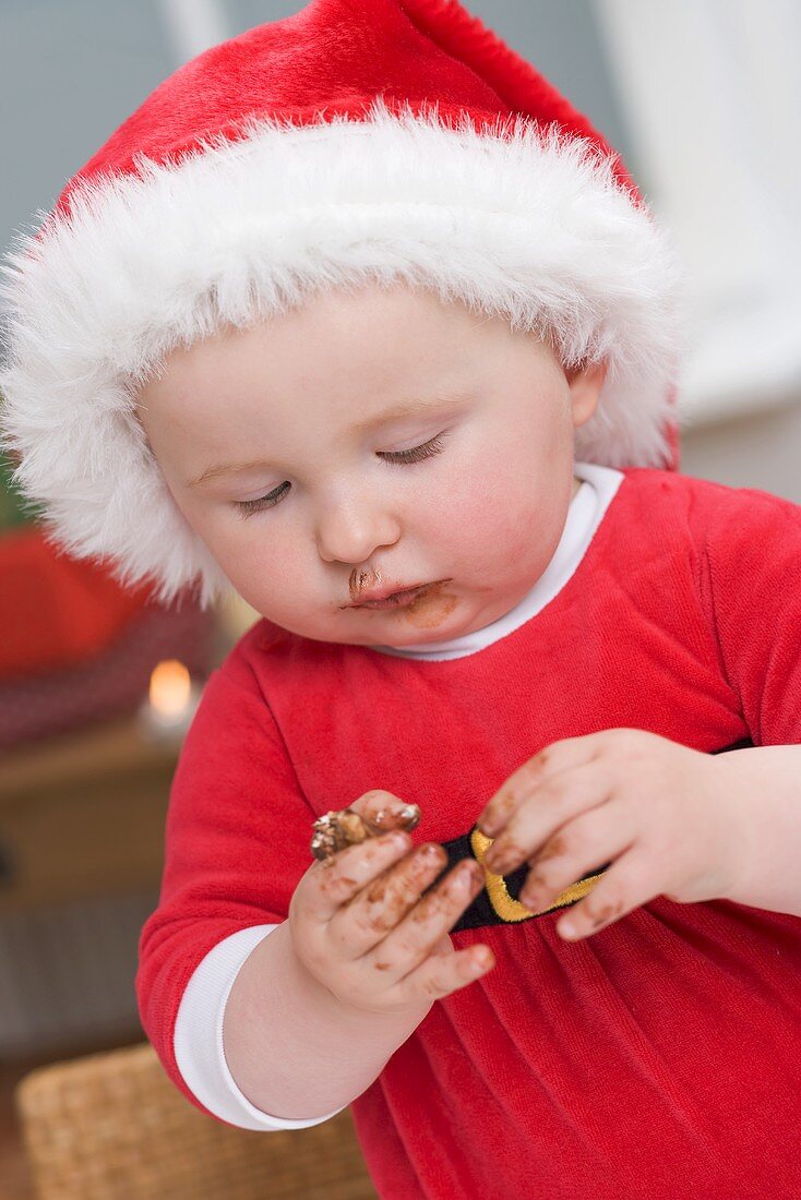 Baby in Father Christmas hat, messy with chocolate