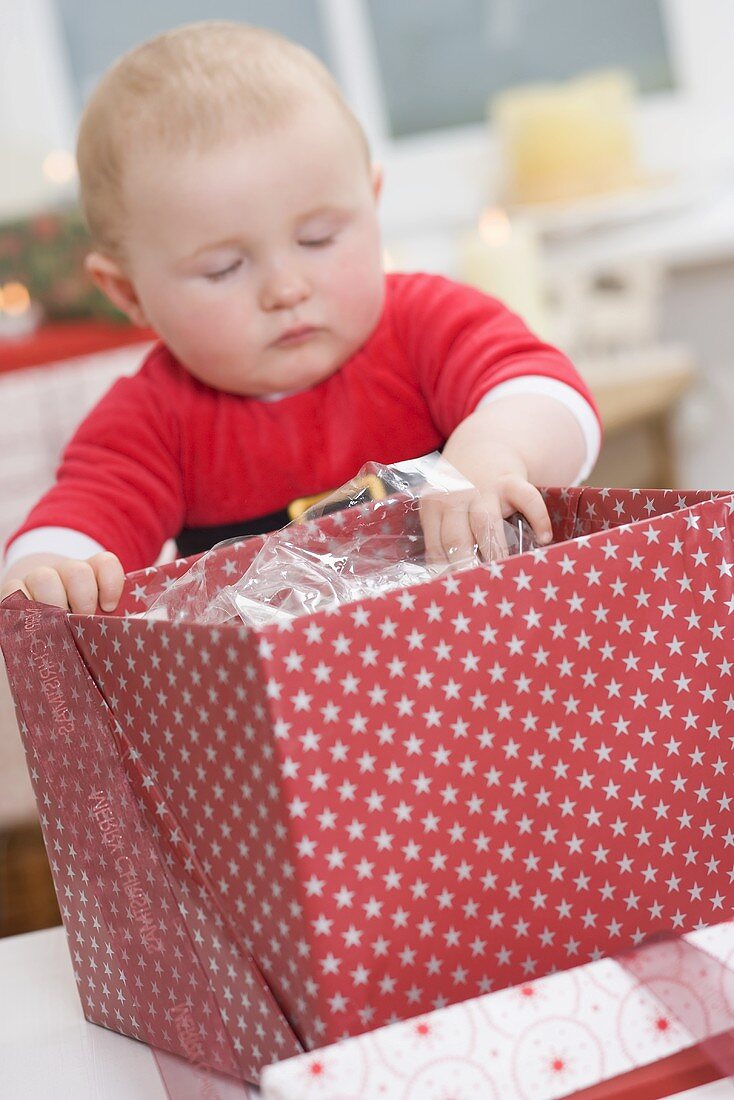 Baby greift in geöffnetes Weihnachtspaket