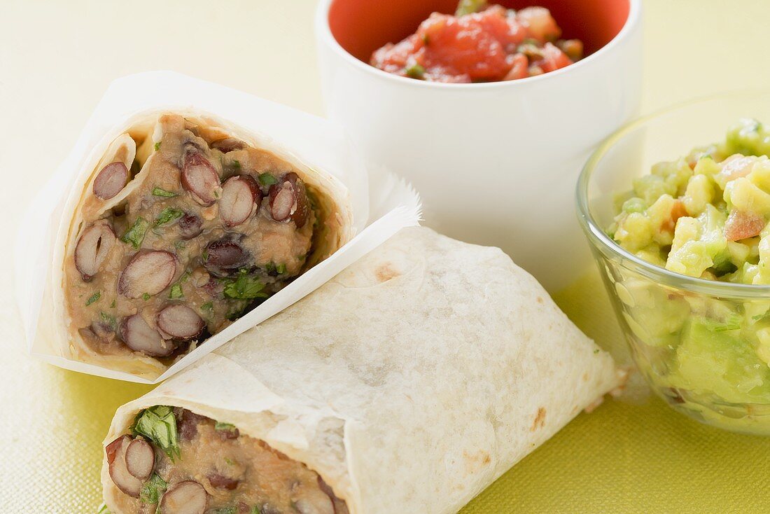 Burritos mit Bohnenfüllung, Guacamole und Salsa in Schälchen