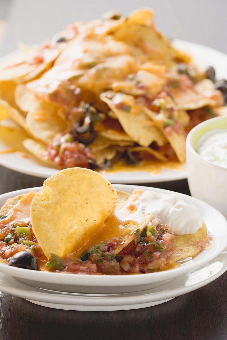 Tortilla chips with melted cheese, olives and sour cream