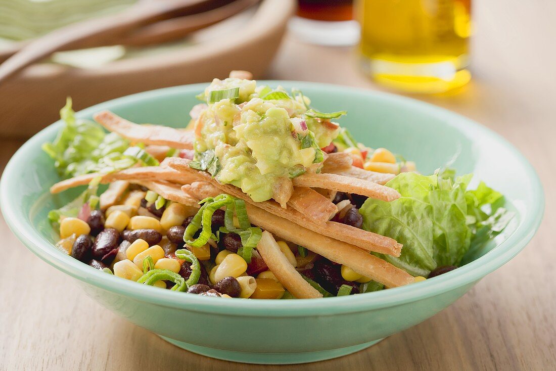 Salat mit Bohnen, Mais, Tortillastreifen und Guacamole