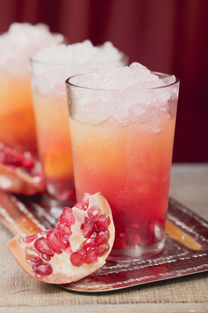 Drei fruchtige Drinks mit Orangensaft und Granatäpfeln