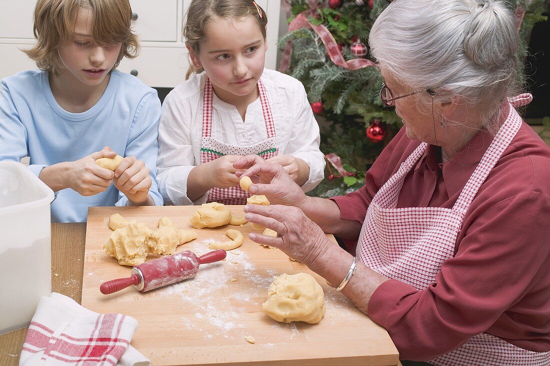 Grossmutter erklärt Enkeln das Formen von Vanillekipferln