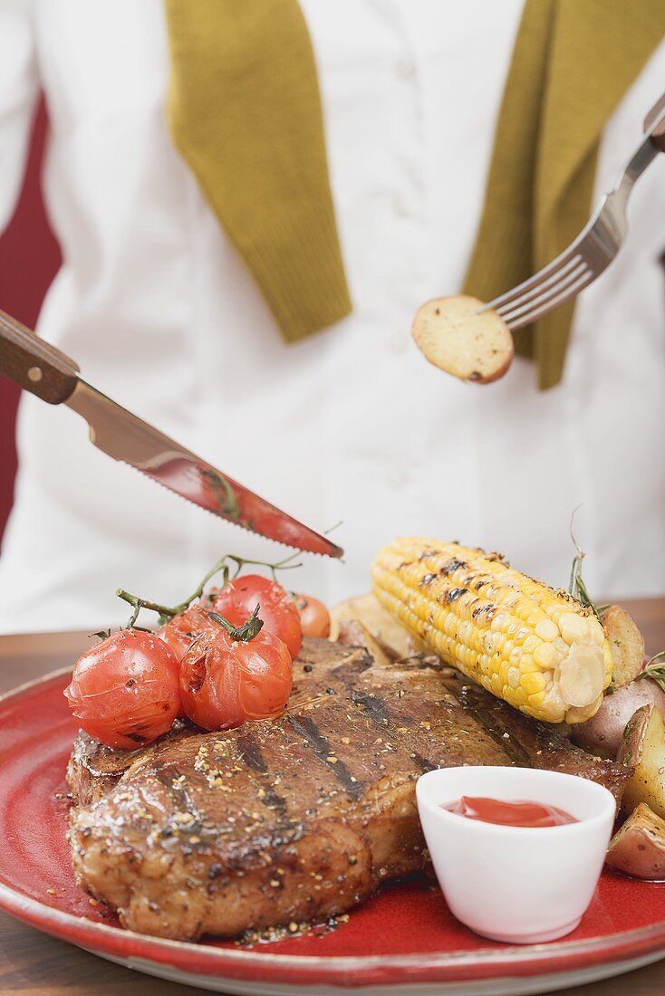 Woman eating T-bone steak with accompaniments