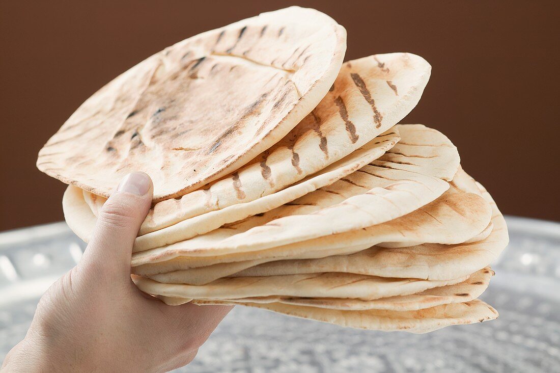 Hand holding several grilled flatbreads
