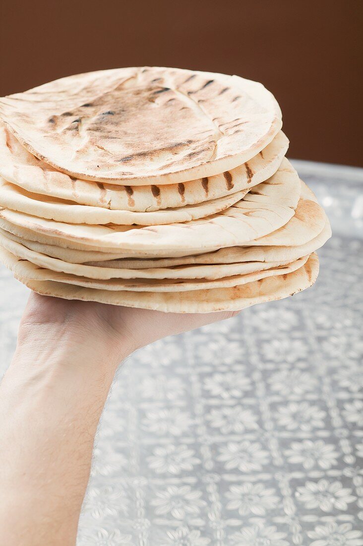 Hand hält gegrillte Fladenbrote (gestapelt)