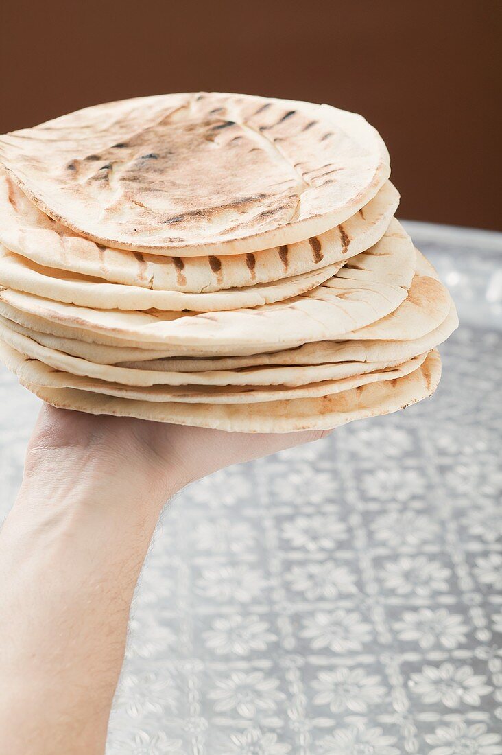 Hand holding stack of grilled flatbread