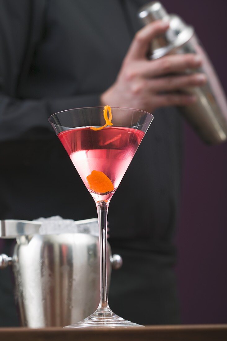 Cosmopolitan in glass, bartender with cocktail shaker