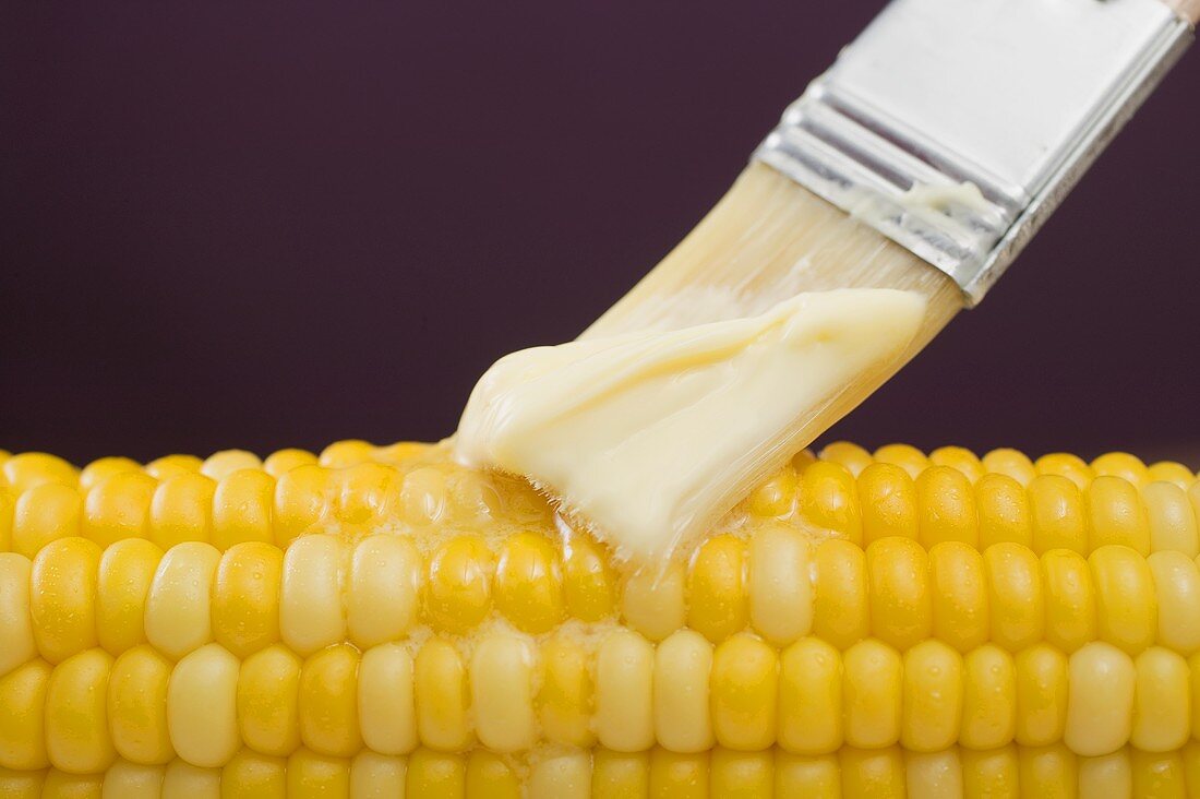 Brushing corn on the cob with butter